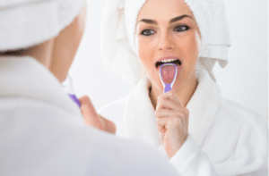 A Woman Looking In Mirror Cleaning Her Tongue