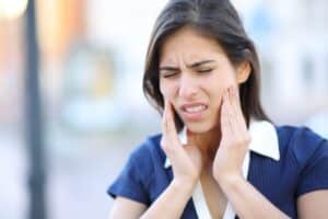 Woman holding her jaw in pain due to TMJ symptoms in McLean, VA