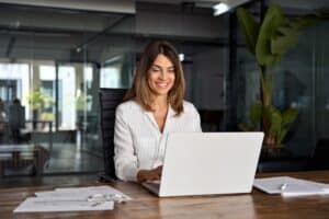 Busy professional smiling at her desk after cosmetic dental procedures in McLean, VA
