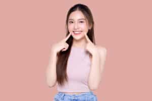 Young girl smiling and pointing to teeth after teeth whitening in McLean, VA