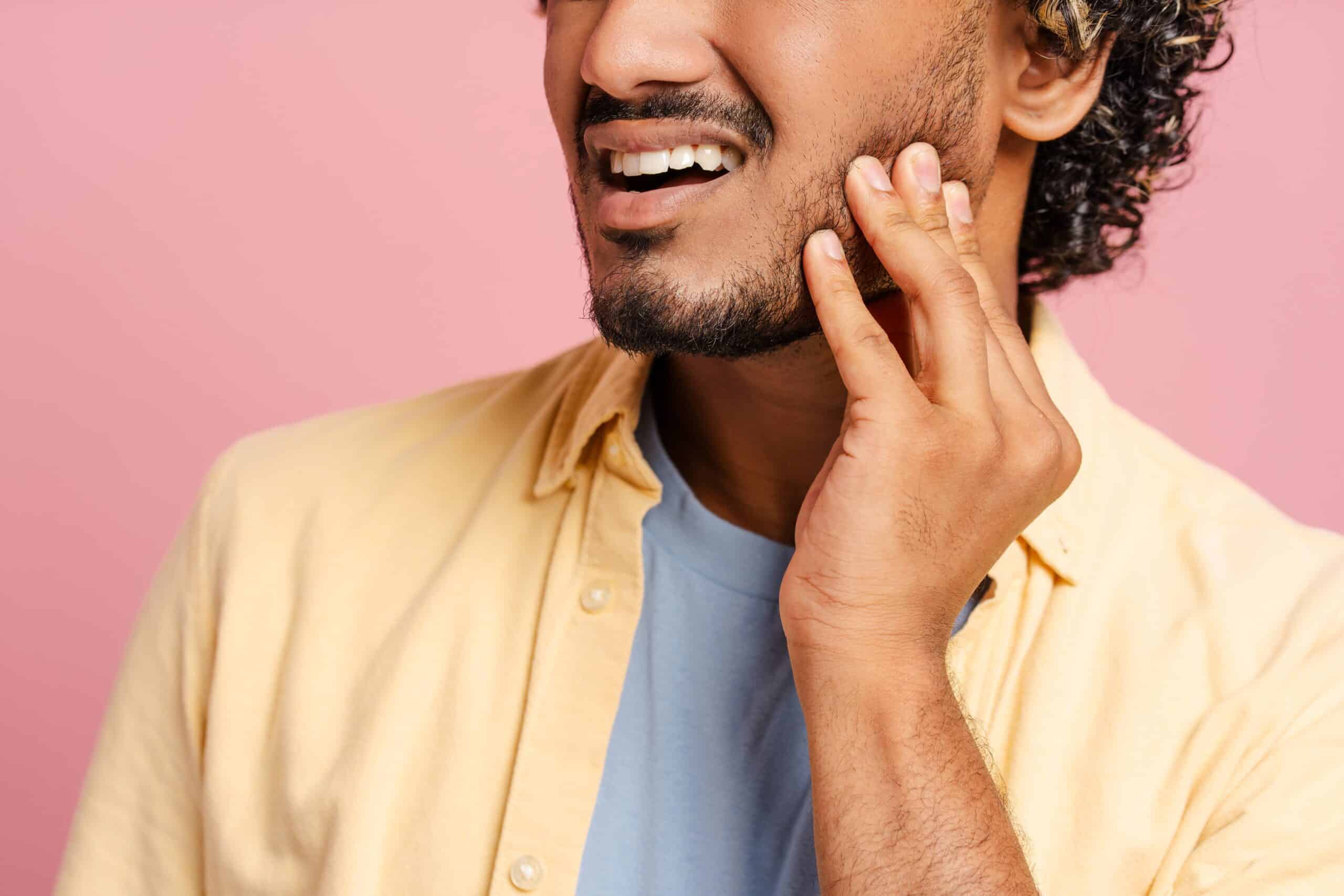 Man holding his jaw from symptom of misalignment needing neuromuscular dentistry
